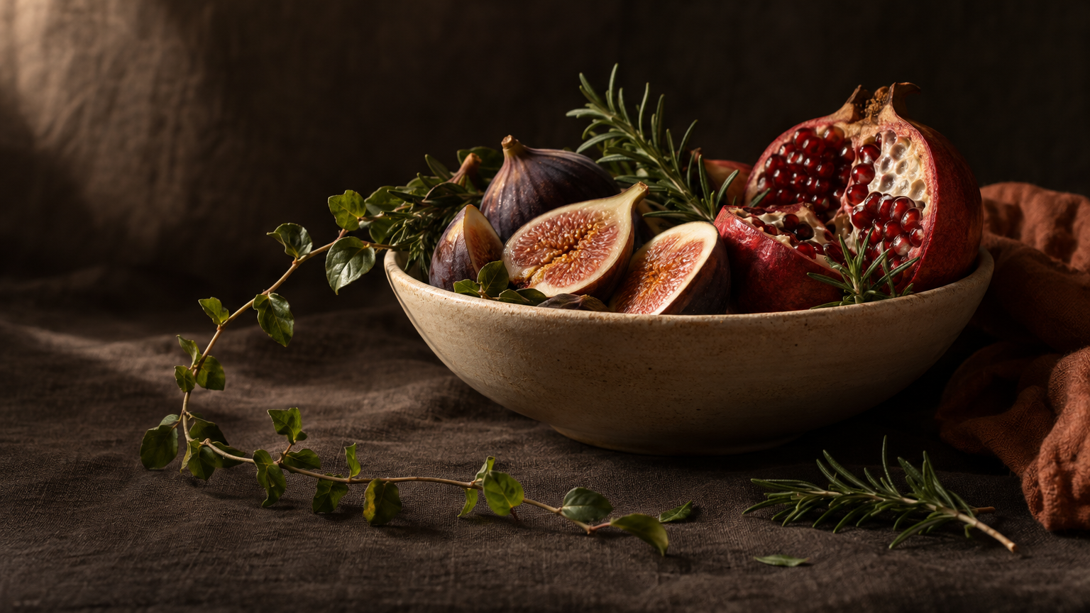 Dark moody still life of figs, pomegranate and rosemary illustrating a sermorelin peptide vs tesamorelin comparison